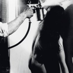 Yves Klein détourant un corps de femme à l'eau lors d'une anthropométrie au cours de la réalisation d'une peinture de feu.